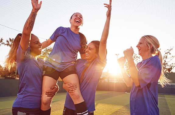 Female soccer players celebrate a victory.
