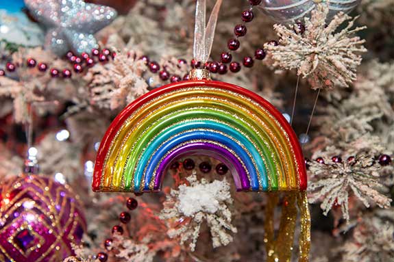 Rainbow ornament hangs on a Christmas tree.