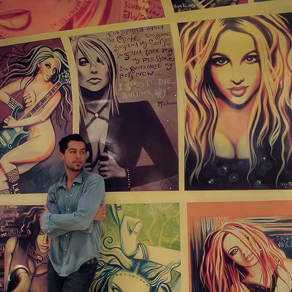 The artist with part of his thirty painting wall/ceiling collage mural installation at Deetour Boutique. Photo by Stephanie Costello.